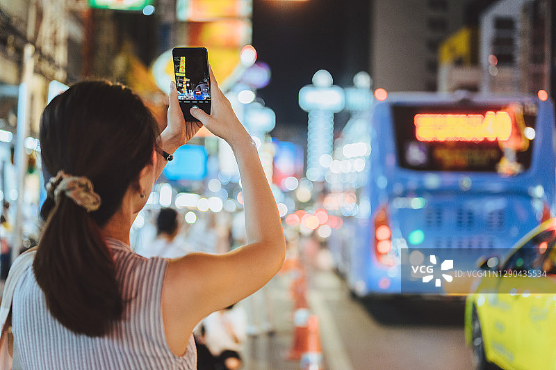 年轻的亚洲人喜欢在曼谷唐人街yaowarat晚上使用智能手机旅行图片素材