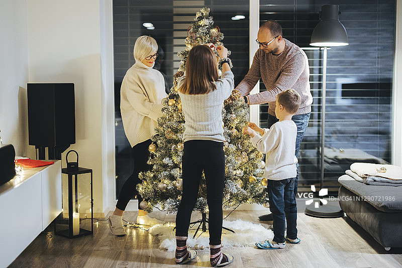 白人四口之家在晚上装饰圣诞树图片素材