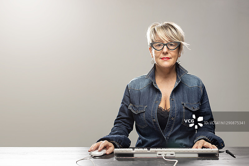 女人坐在办公桌前使用鼠标和键盘的肖像图片素材