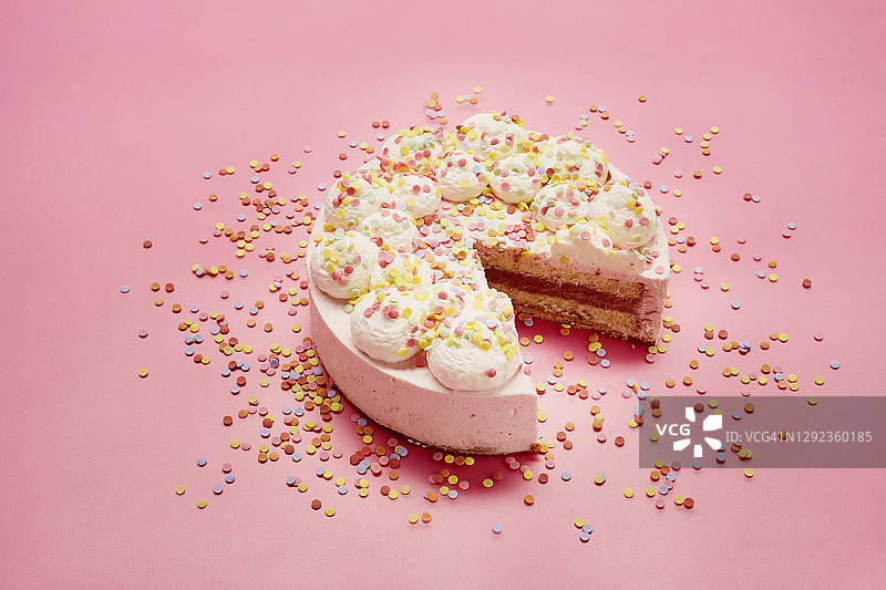 高角度的奶油蛋糕和彩色的糖洒在粉红色的背景图片素材
