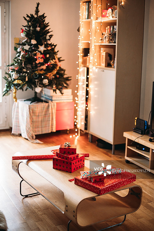 礼物被包裹在客厅的咖啡桌上，在圣诞树和小花环前图片素材