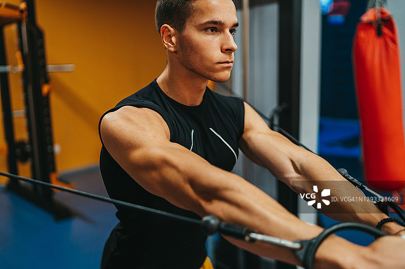 帅哥在健身房用滑轮做三头肌运动图片素材