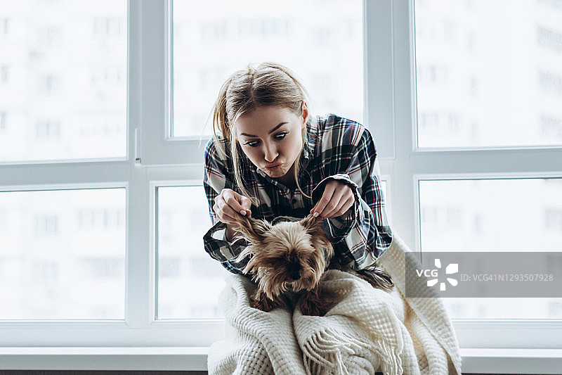 一个年轻漂亮的女人牵着小狗的耳朵玩图片素材