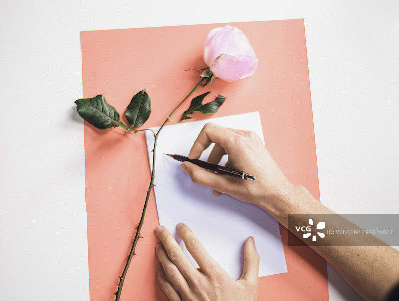 一只写着粉红色背景的情书的手图片素材