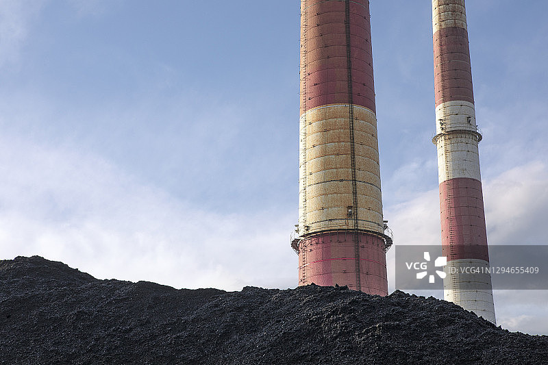 煤堆，有工业烟囱的天然黑煤。工业背景。全球变暖，二氧化碳排放，煤炭能源问题，化石燃料能源，空气污染，气候变化问题。图片素材