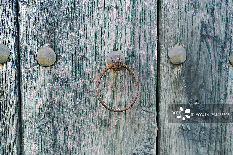 古董木门上的圆形门把手是用生锈的金属制成的图片素材
