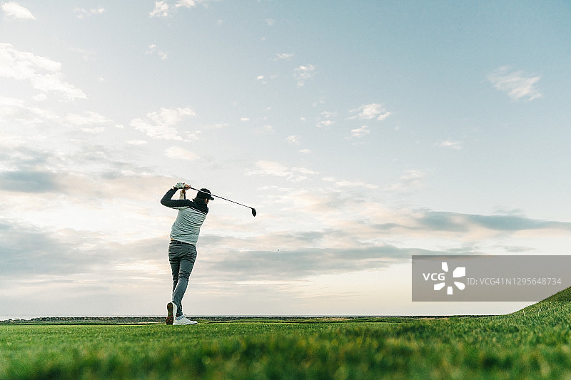男性高尔夫球手在日落时挥动球杆图片素材