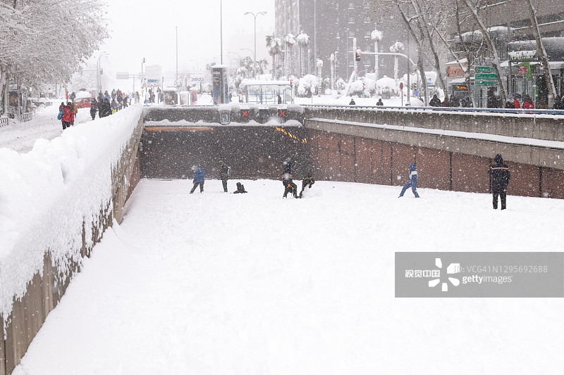 人们在一个被雪覆盖的隧道中行走和玩耍，因为汽车不能通过雪。菲洛梅娜风暴给马德里带来了一场大雪图片素材