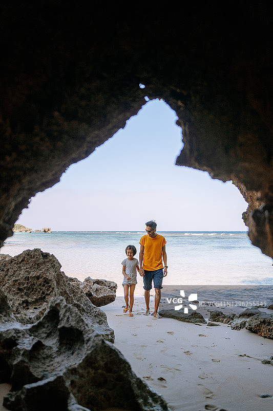 父亲和年幼的女儿在僻静的海滩与洞穴图片素材