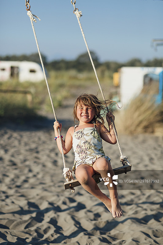 一个美丽的小白人女孩在海滩上荡秋千的特写图片素材