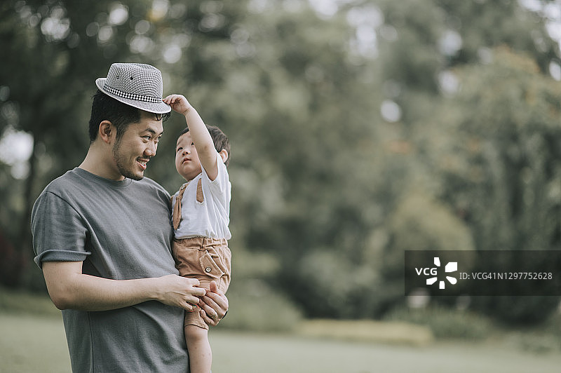 一位亚洲华人父亲周末带着儿子在公园玩帽子图片素材