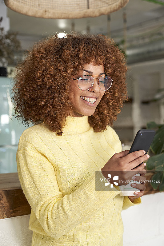 微笑的女人在咖啡店使用智能手机图片素材