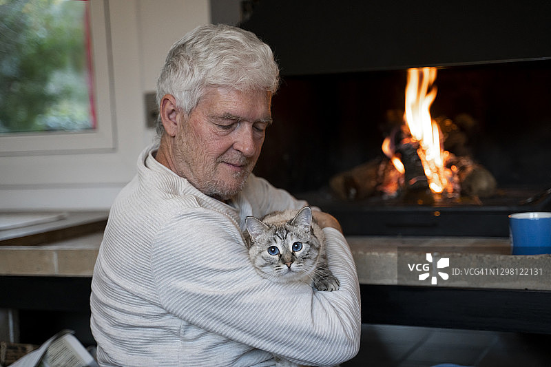 老人坐在壁炉旁抱着猫图片素材
