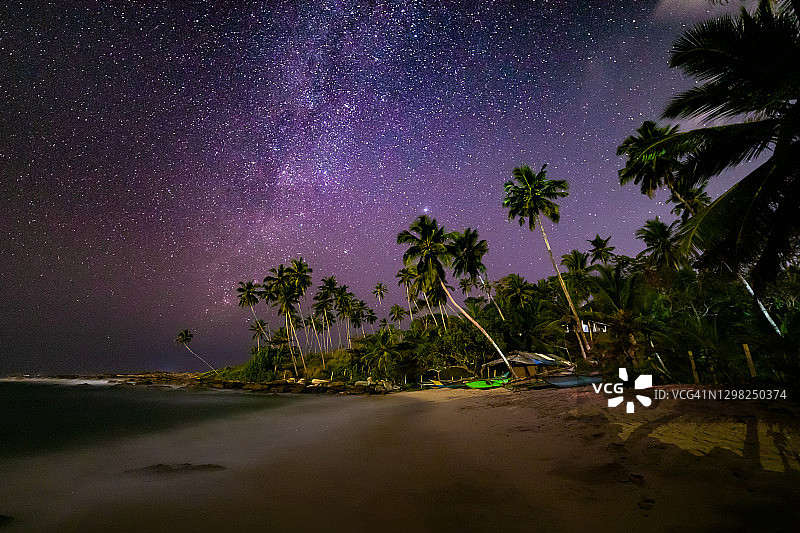 银河的沙滩上有船和棕榈树。斯里兰卡图片素材
