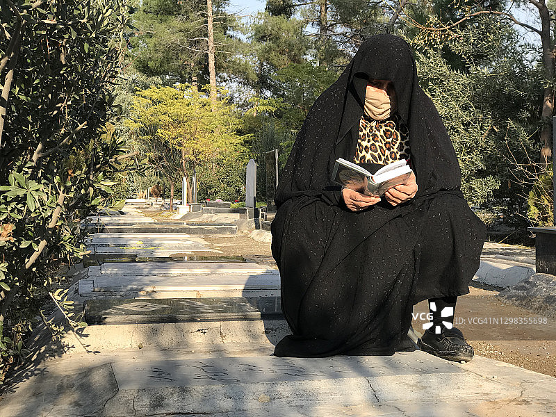 在伊朗德黑兰的公共公墓，一名妇女正在为死于冠状病毒的丈夫祈祷图片素材