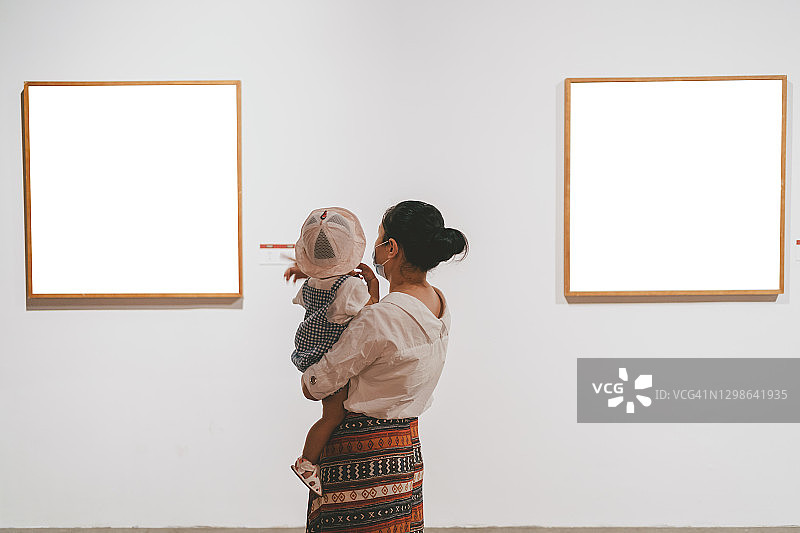 亚洲妇女和她的孩子在画廊观看展览图片素材