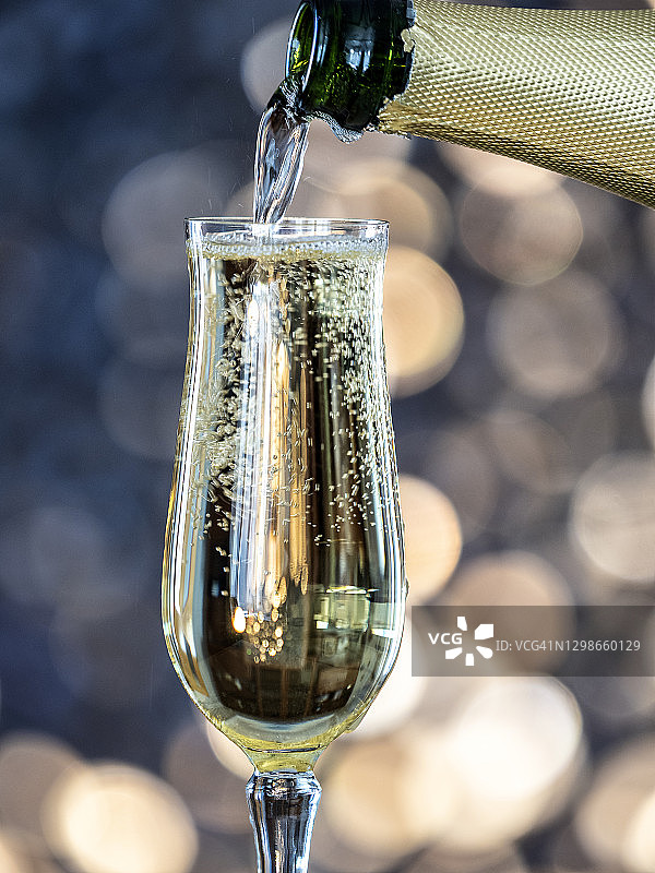 一杯香槟和一瓶以圣诞彩灯为背景的酒。图片素材