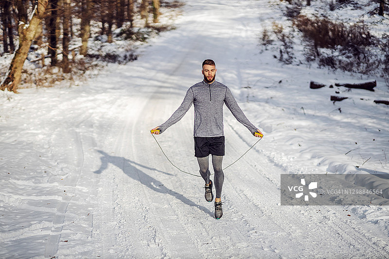雪天，健硕运动员在大自然中跳绳。冬季健身，有氧运动图片素材