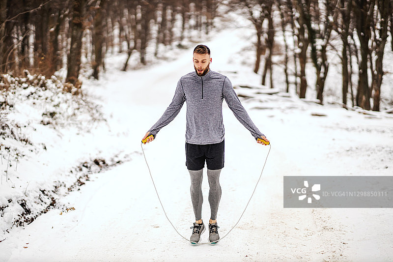 雪天，运动员在大自然中跳绳。冬季健身，健康生活，有氧运动图片素材