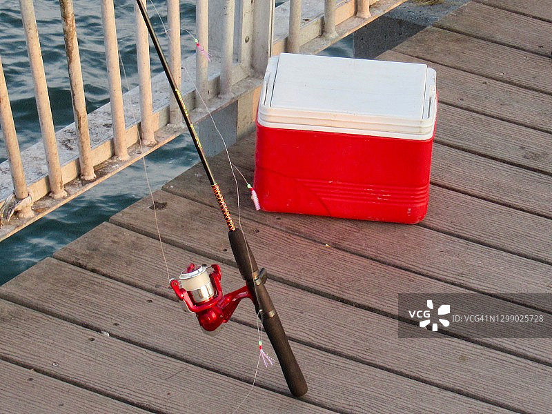 钓鱼:码头边的冷却器旁的钓竿和鱼线图片素材