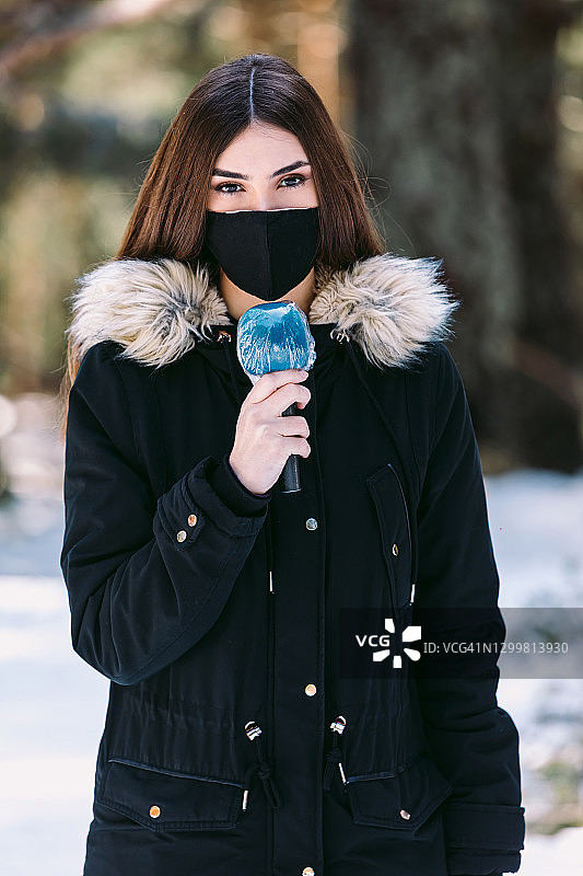 戴着防护口罩在大雪中播报新闻的电视女记者图片素材