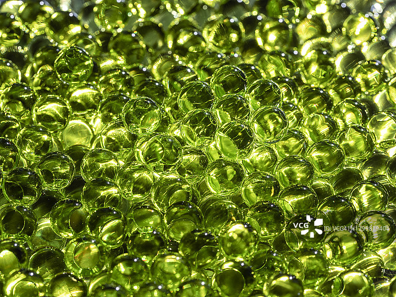 满框架的玻璃球堆与反射和闪烁的光绿色的光。图片素材