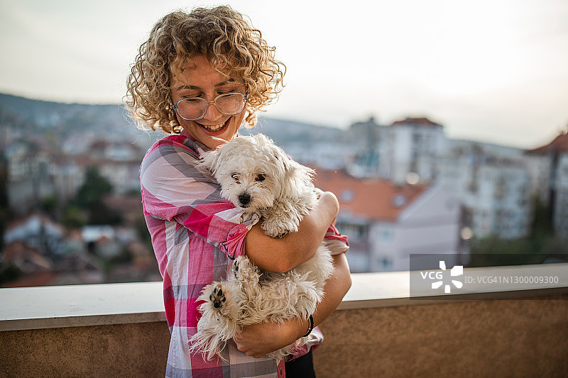 阳台上的年轻女子和她的白色小狗图片素材