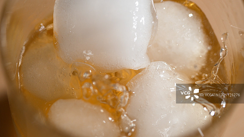 MACRO:将新鲜的冰块放入装满威士忌和融化的冰块的玻璃杯中图片素材