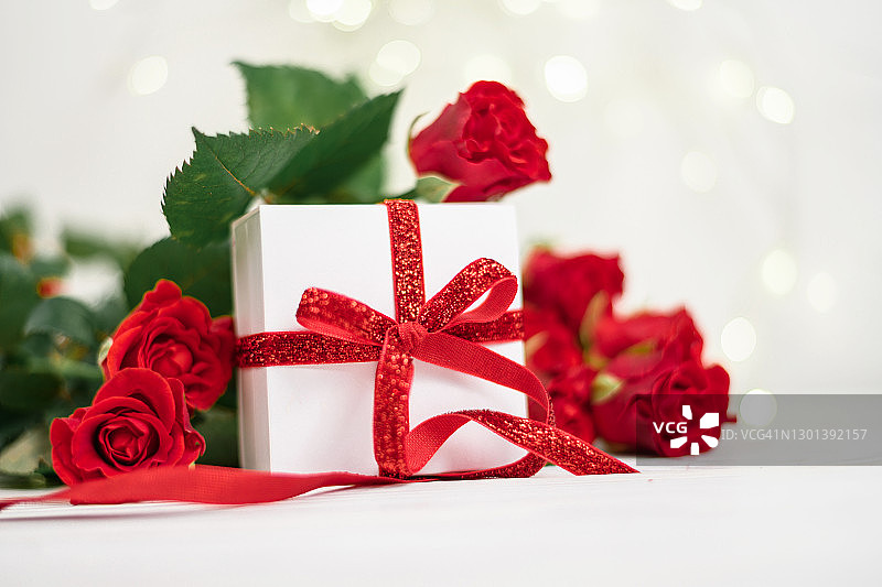 白色的礼盒，红色的蝴蝶结，红色的玫瑰和bokeh背景，祝贺圣瓦伦丁节，母亲节，3月8日图片素材