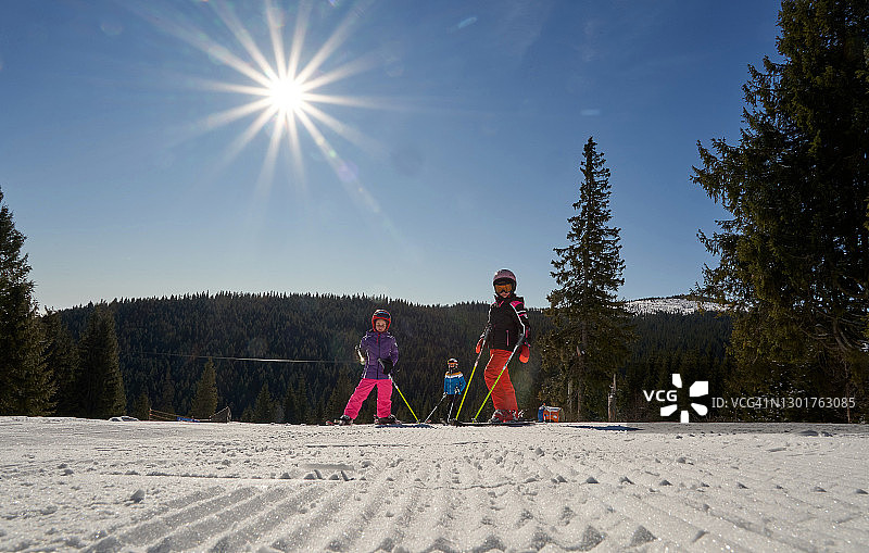 三个女孩在滑雪场，母亲和女儿穿着滑雪服站在滑雪坡上享受滑雪假期。图片素材