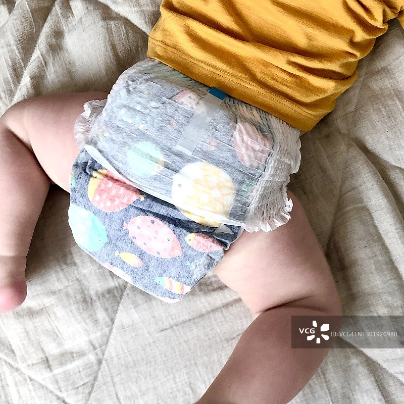 男婴穿着婴儿尿布躺在床上，选择性聚焦图片素材