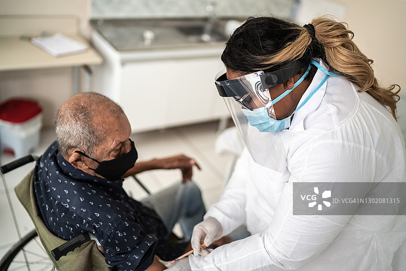 成熟医生为戴口罩的老人接种疫苗图片素材