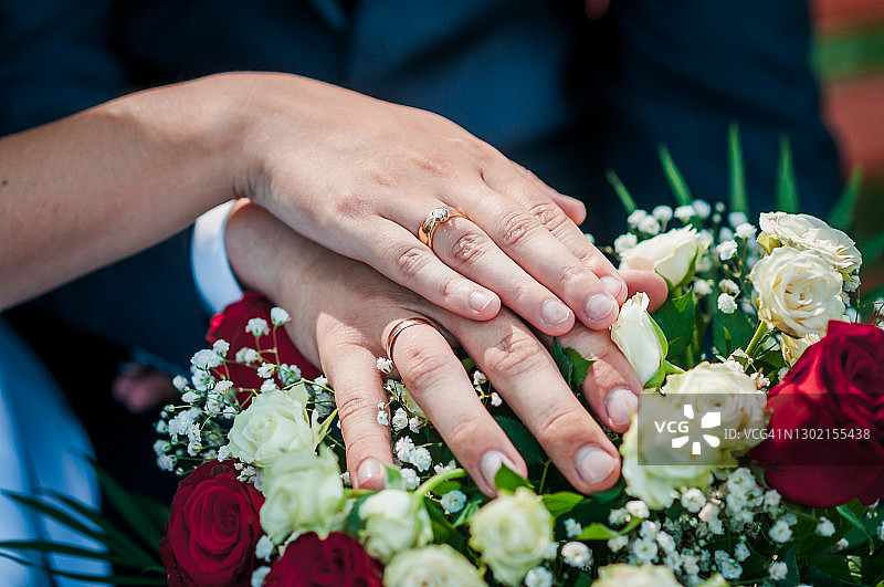 在婚礼花束上，新婚夫妇手上戴着结婚戒指图片素材