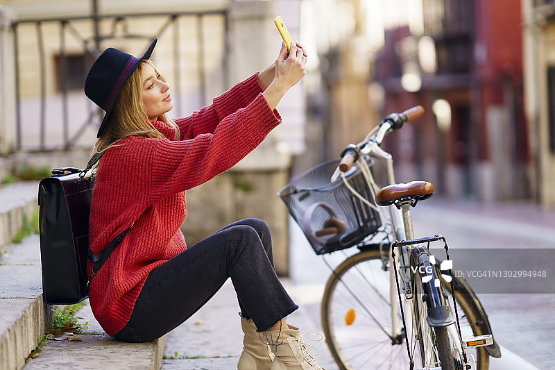 坐在台阶上骑自行车的女人用手机自拍图片素材