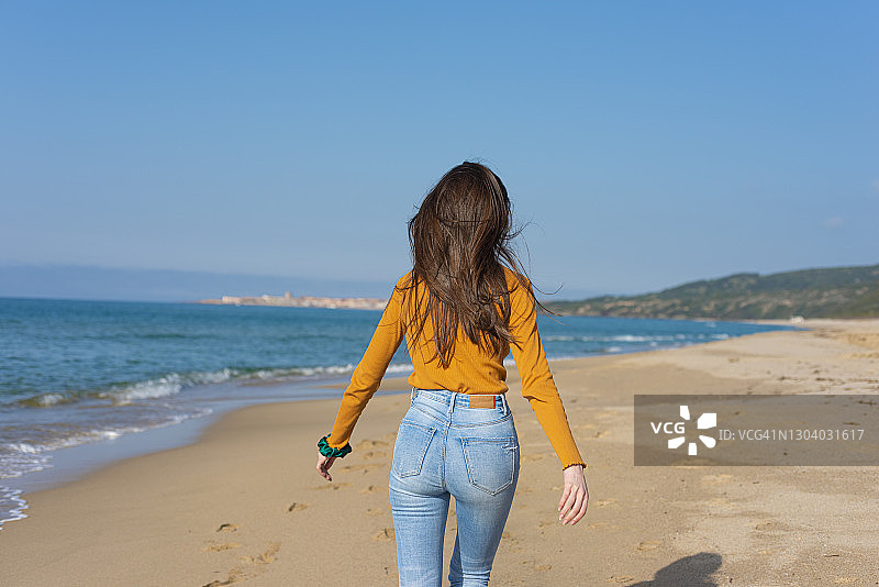 年轻的成年女子在海滩上散步图片素材