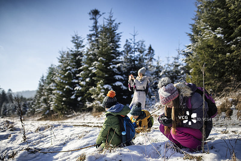 妈妈和孩子们喜欢在冬天的山上徒步旅行。图片素材