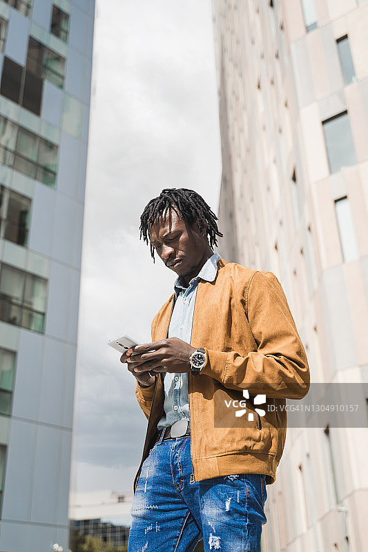 非洲年轻人在现代城市的商业区使用智能手机图片素材
