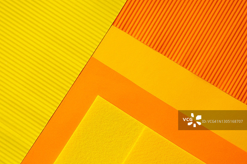背景由几层纸制成，这些纸的颜色是今年最流行的:明亮的黄色和橙色。平躺风格图片素材