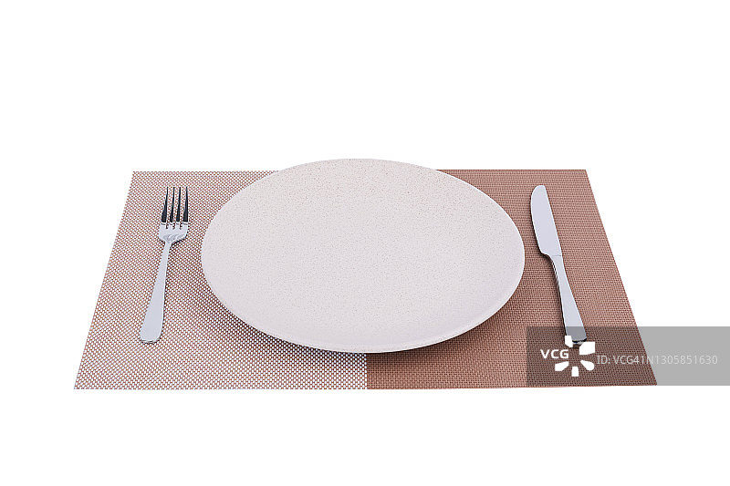 吃饭的地方设置。餐具垫上有一个瓷盘子，上面有银的刀叉，孤立在白色的背景上图片素材