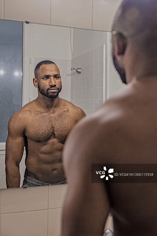 裸胸男子在浴室镜子里看着自己图片素材