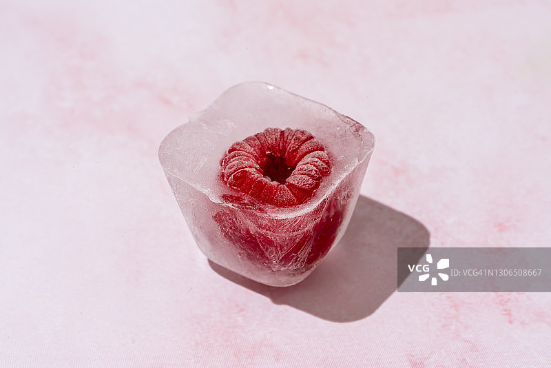 粉红色大理石表面的冰立方里的冰冻覆盆子图片素材