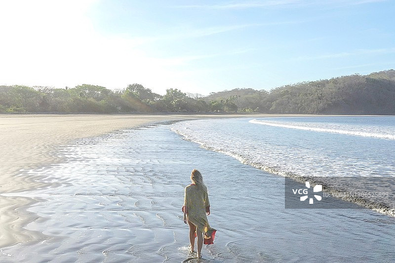 一名年轻女子早晨在沙滩上散步图片素材