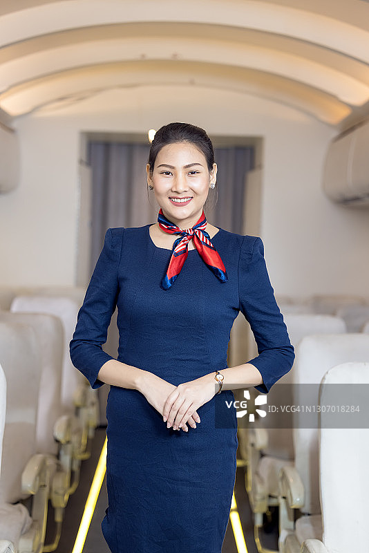 亚洲空乘人员在飞机乘客座位的过道中间微笑图片素材