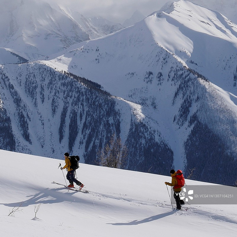 清晨，偏远地区的滑雪者登上雪山山脊图片素材