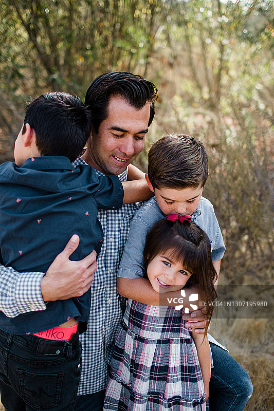 父亲抱着三个孩子在圣地亚哥的野外图片素材