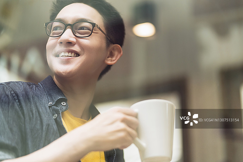 聪明自信的亚洲创业企业家企业主商人微笑手握咖啡杯在咖啡馆背景工作图片素材