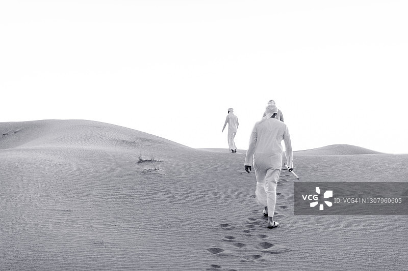 一群阿拉伯人在爬沙丘图片素材