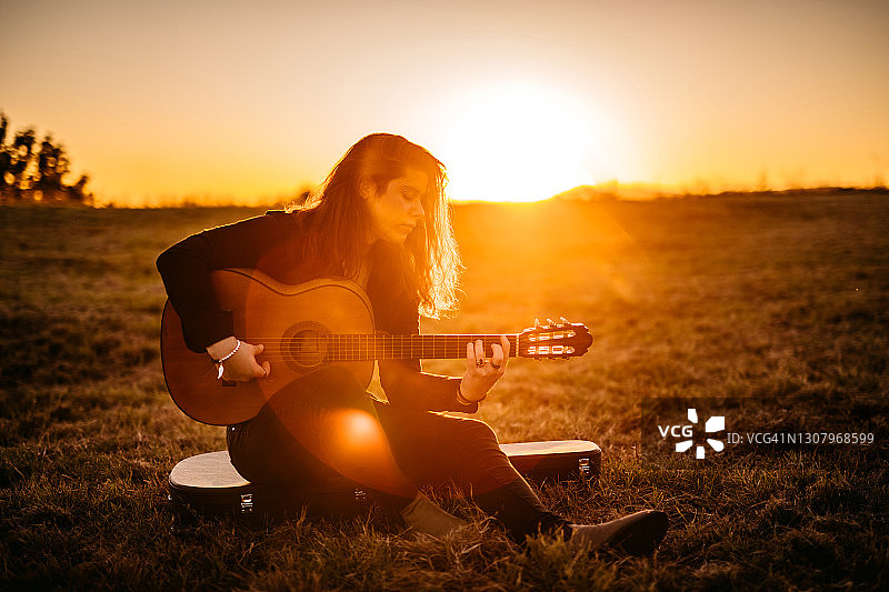一个年轻人在日落时弹吉他图片素材