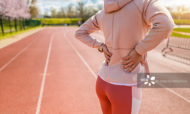 不知名的年轻运动女性背部疼痛。图片素材