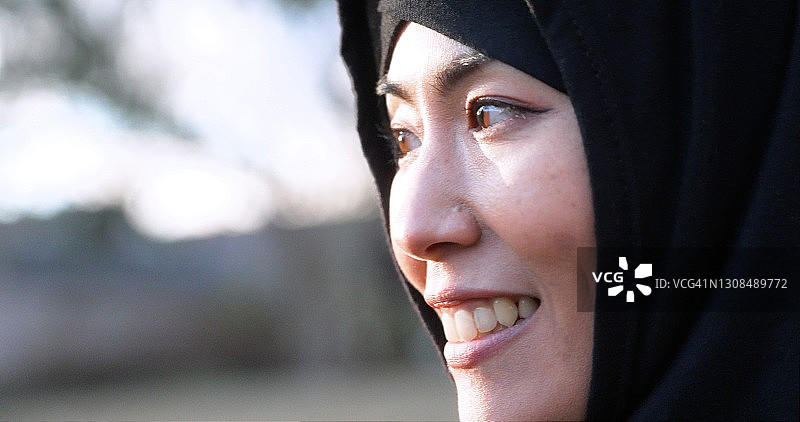 一个微笑的中年亚洲穆斯林妇女戴着头巾的档案图像图片素材